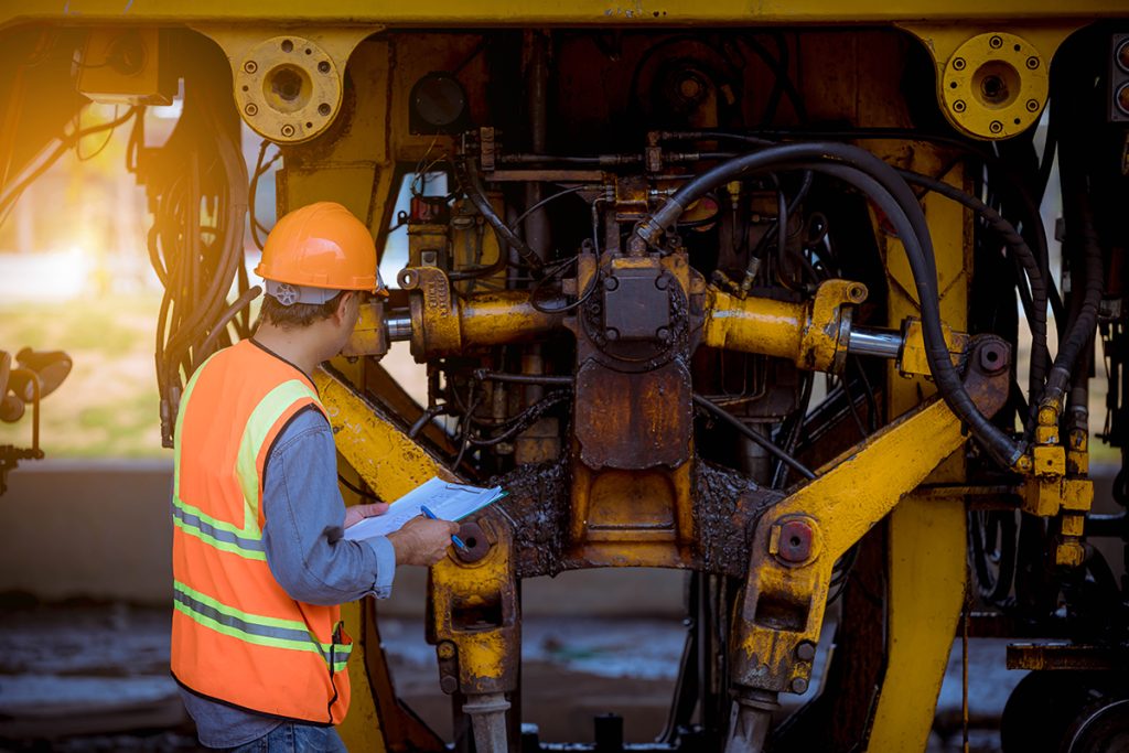 An engineer checking on a heavy machine outside